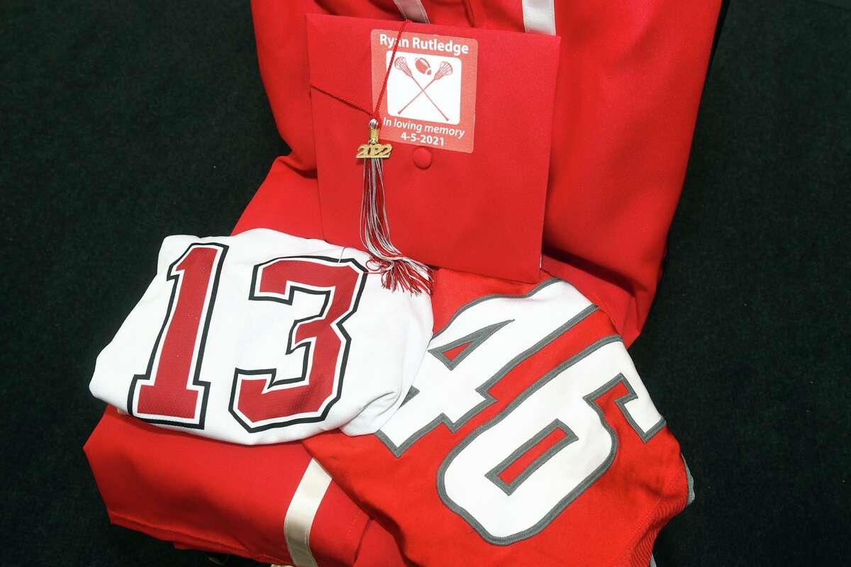 A cap and gown laid out along with lacrosse and football jerseys in memory of Ryan Rutledge during Commencement for the Pomperaug High School Class of 2022, in Southbury, Conn.  June 20, 2022.