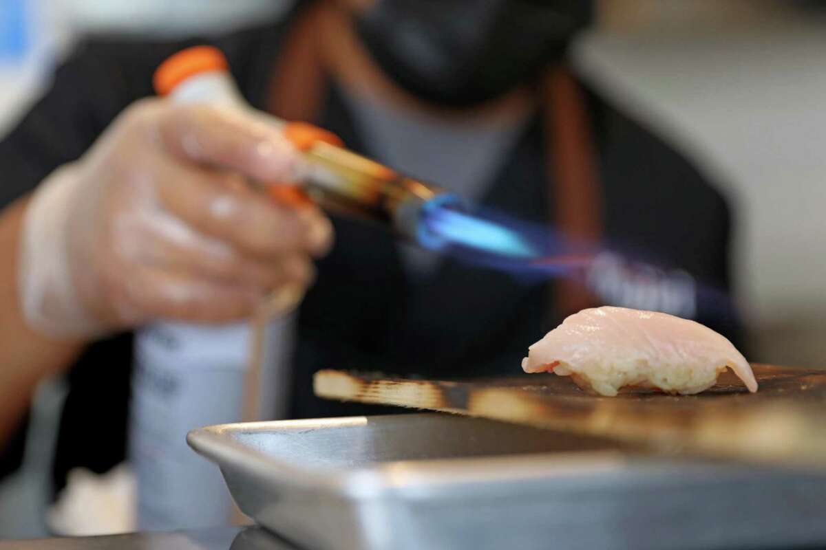 Jeremias Jimenez burns fish at Mujiri, which is becoming a community favorite for sushi in North Oakland.