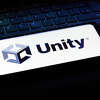 In this photo illustration the Unity Technologies logo seen displayed on a smartphone on the background of a keyboard. 