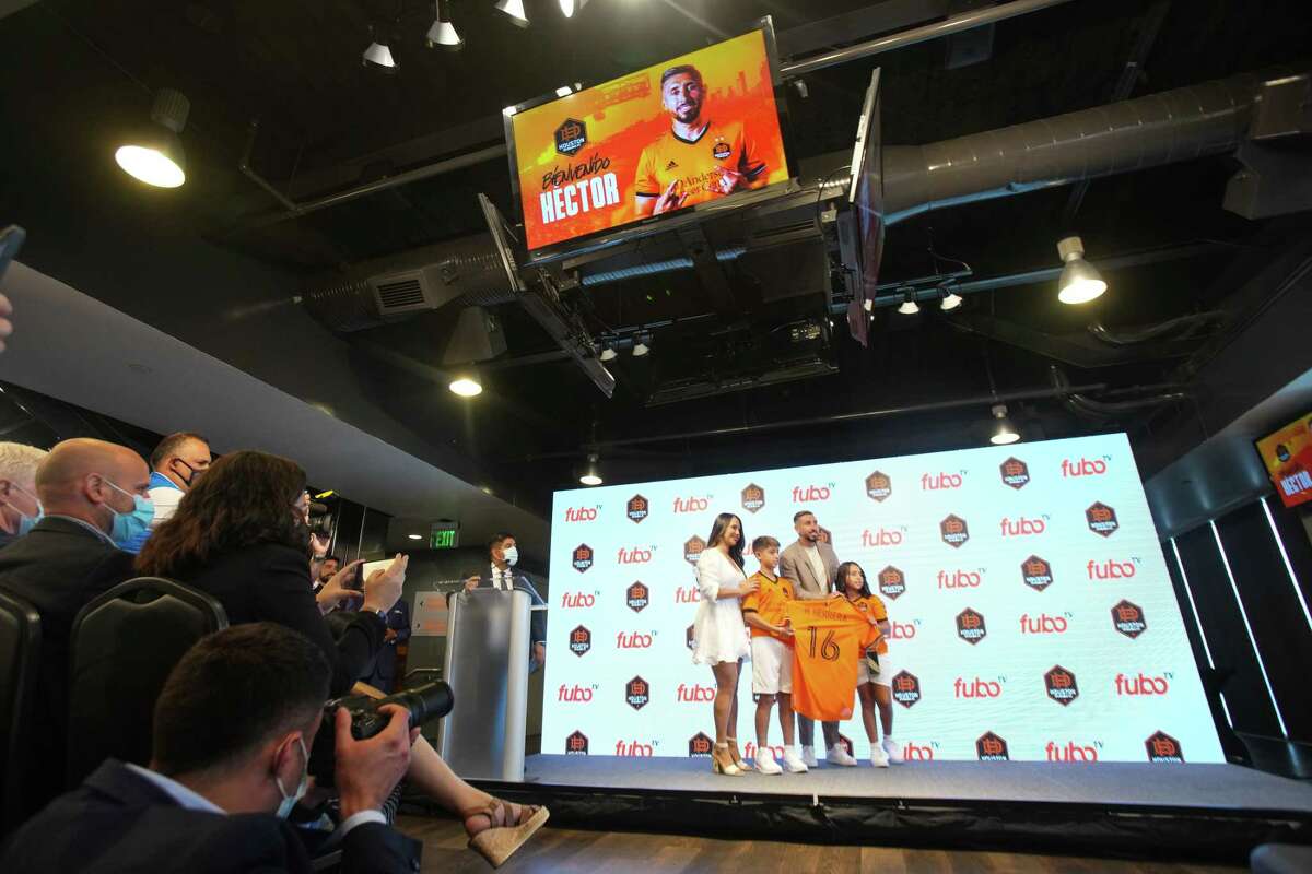 Houston Dynamo midfielder Héctor Herrera shows off his jersey as he poses for photos with his family during an introductory news conference Friday, July 1, 2022 in Houston. Herrera, the highest-profile international signing in Dynamo history, is a captain with the Mexican national team and comes to Houston from Atlético de Madrid in Spain.