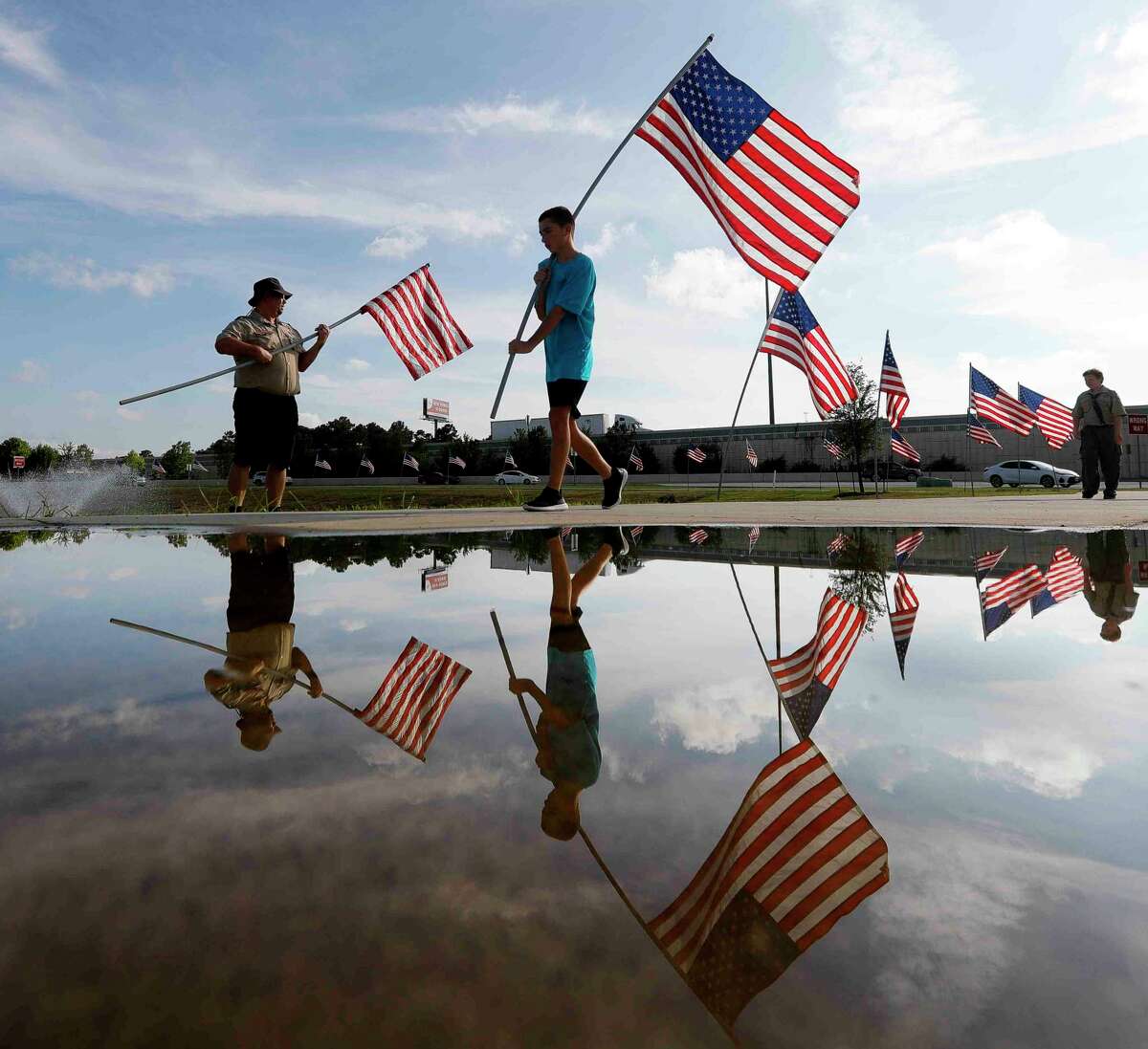 Boy Scout Aidan Lyon, center, carries an American flag as scouts with Troop 1417 and 776 placed 100 flags around the Montgomery County Veterans Memorial Park ahead of the Fourth of July weekend, Friday, July 1, 2022, in Conroe. The park, at Interstate 45 and Texas 105, was shaped by former United States Marine Corps Cpl. Jimmie Edwards III. Edwards, who also served as county judge, began his effort to move and expand the park in 2017. The park honors all veterans who have served and those killed in action.