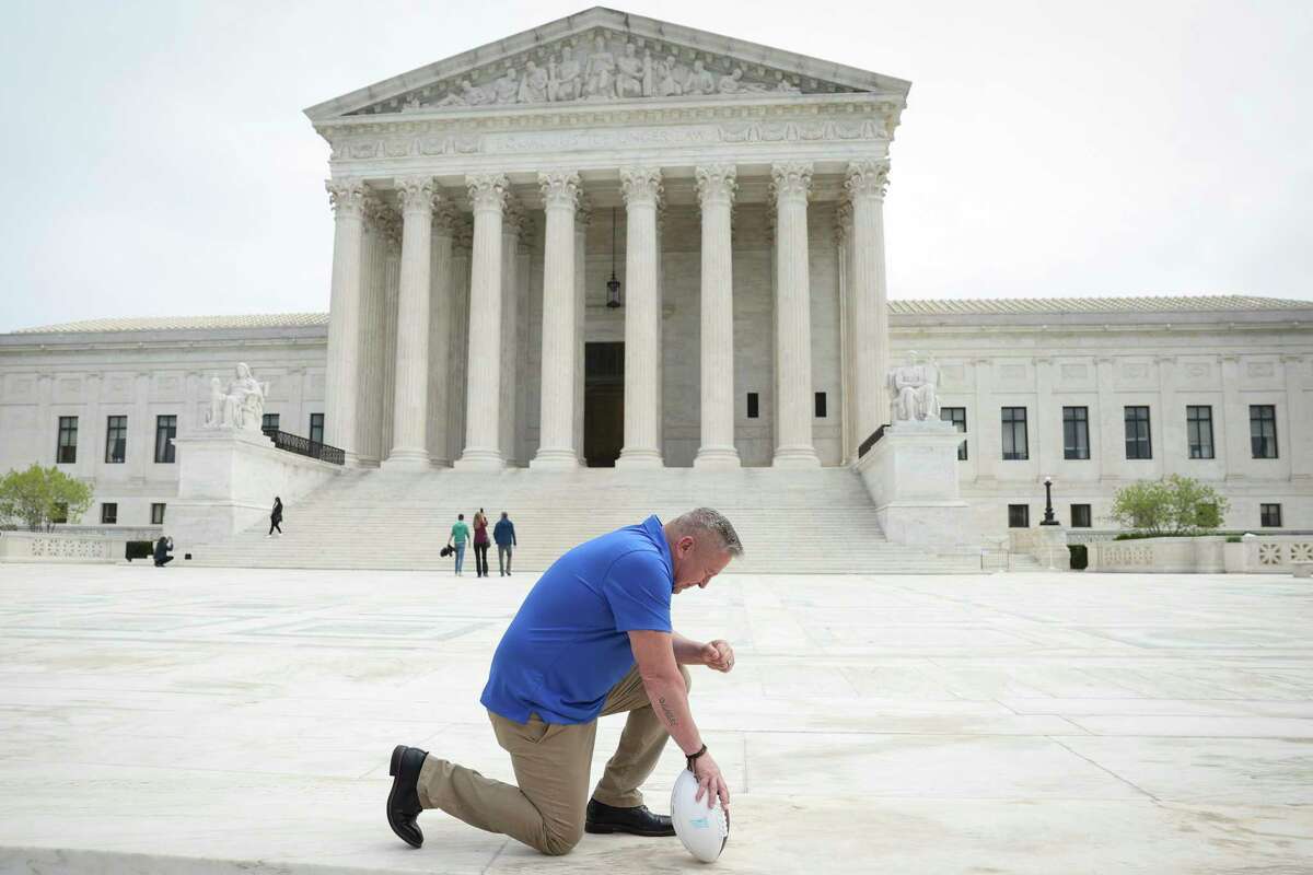 Former Bremerton (Wash.) High School assistant football coach Joe Kennedy takes a knee in front of the U.S. Supreme Court after his legal case, Kennedy vs. Bremerton School District, was argued before the court on April 25. Kennedy was terminated from his job by Bremerton public school officials in 2015 after refusing to stop his on-field prayers after football games.