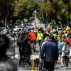 People walk and cycle along Lake Street during a community parade in support of the slow street in San Francisco’s Richmond District on April 30, 2022.
