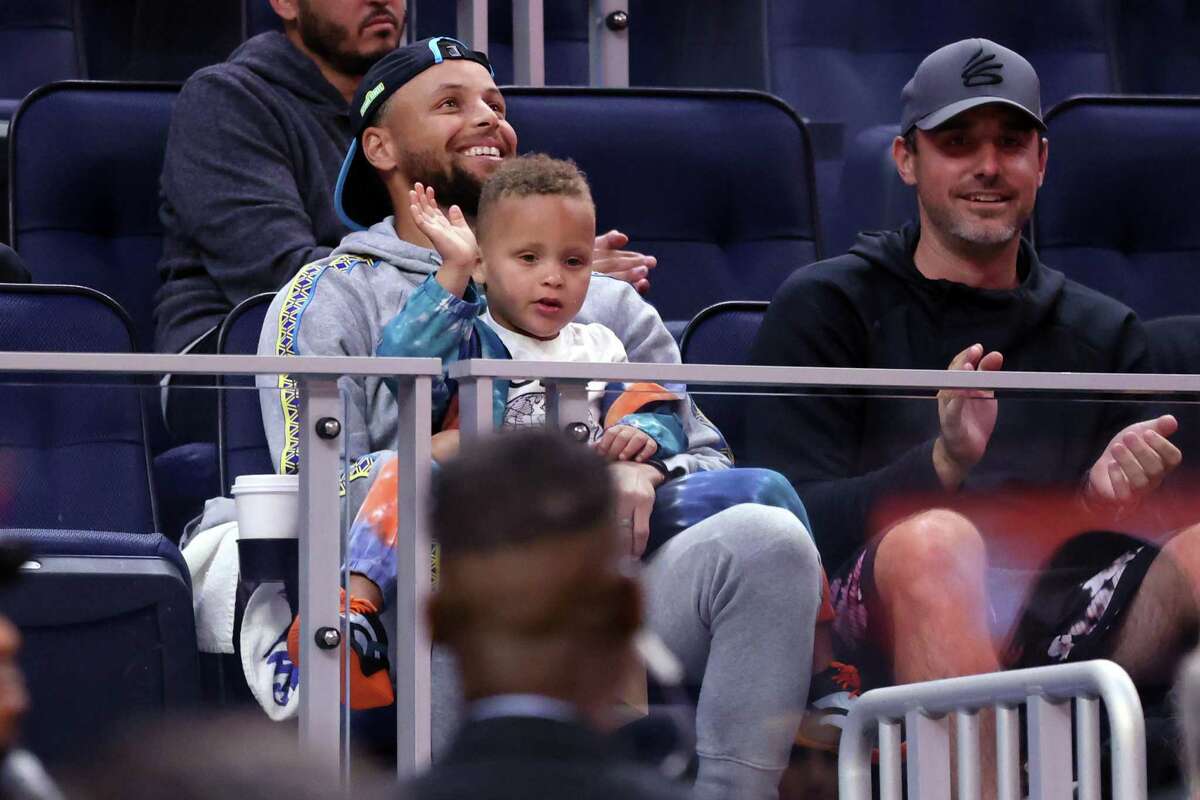Golden State Warriors’ Stephen Curry and his son, Canon, watch Warriors play Sacramento Kings during California Classic at Chase Center in San Francisco, Calif., on Saturday, July 2, 2022.