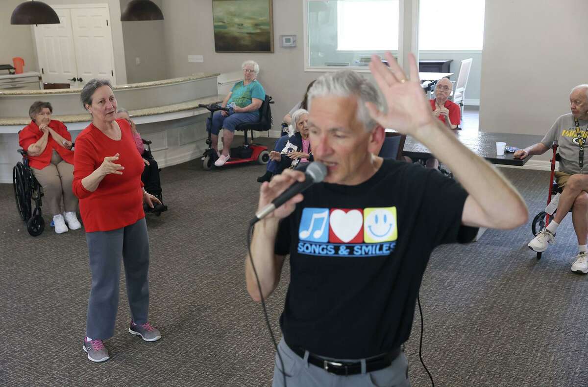 Susan Norris dances as Eric Kolb, a founder of the nonprofit Songs & Smiles, spins while singing with residents at Villagio Senior Living in Carrollton. Kolb has visited the residents to sing twice a month over the last year.