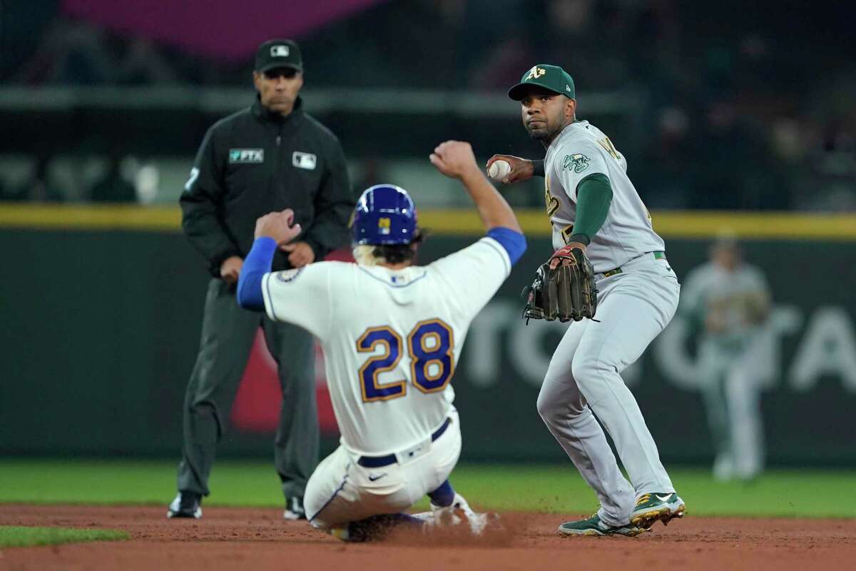 Seattle Mariners' Eugenio Suarez (28) is forced out at second as Oakland Athletics shortstop Elvis Andrus, right, makes the throw to first in time for a double play to put out Mariners' Carlos Santana during the first inning of a baseball game, Sunday, July 3, 2022, in Seattle. (AP Photo/Ted S. Warren)