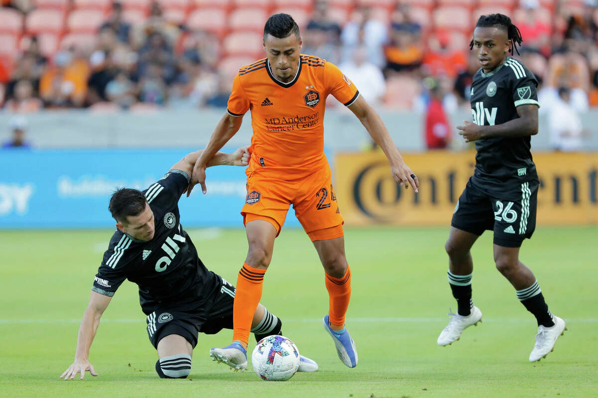 Houston Dynamo midfielder Darwin Ceren (24) advances the ball as Charlotte FC midfielder Brandt Bronico, left, goes down on the play while Charlotte FC forward Yordi Reyna (26) looks on during the first half of an MLS soccer match Sunday, July 3, 2022, in Houston. (AP Photo/Michael Wyke)