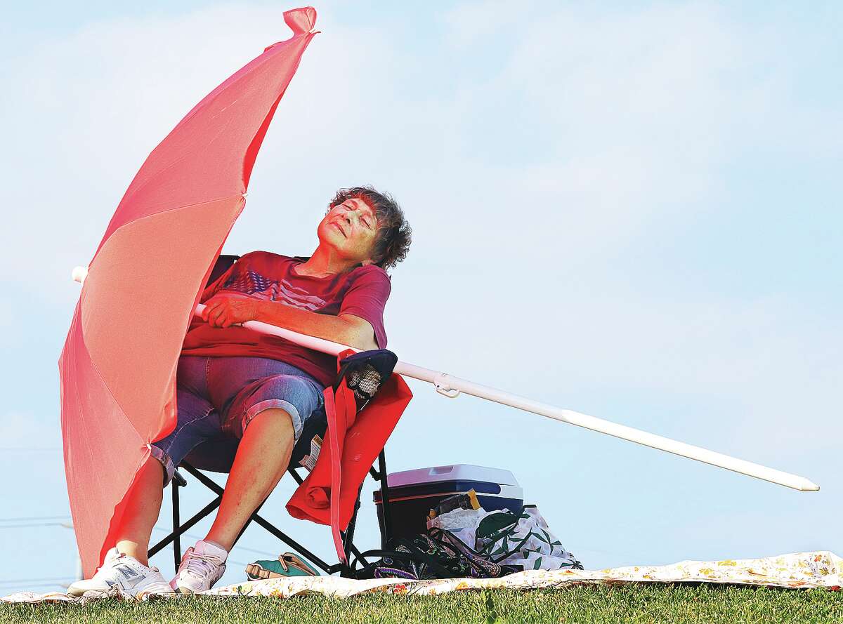 John Badman|The Telegraph Dottie Shaffer of St. Charles, Missouri, brought a super sized umbrella to Alton Sunday to shade herself. She said she was the designated "spot saver" for friends and family who were on their way to join her on the levee near Riverfront Park.