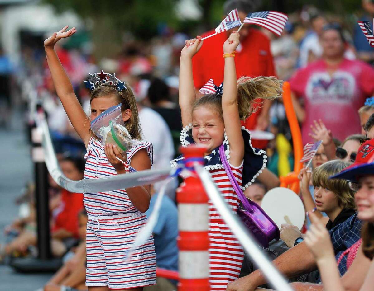 Harper Peringer, center, cheers beside Layla Craine as law enforcement make their way down the street during the annual Fourth of July parade through Market Street on Monday in The Woodlands. The parade featured more than 150 entries that paraded along the 1.3-mile route.