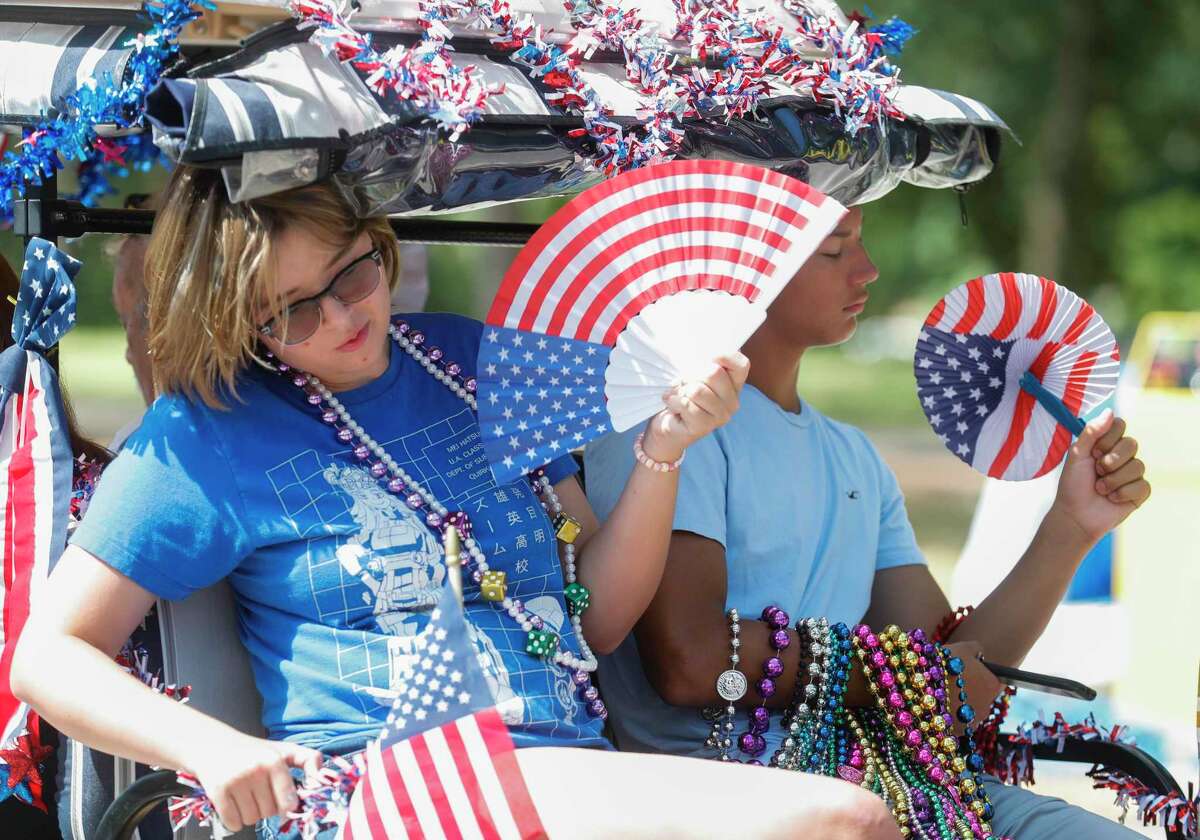 Tristen Tabor cools off with a patriotic fan during the annual Fourth of July parade through Panorama Village, Monday, July 4, 2022.