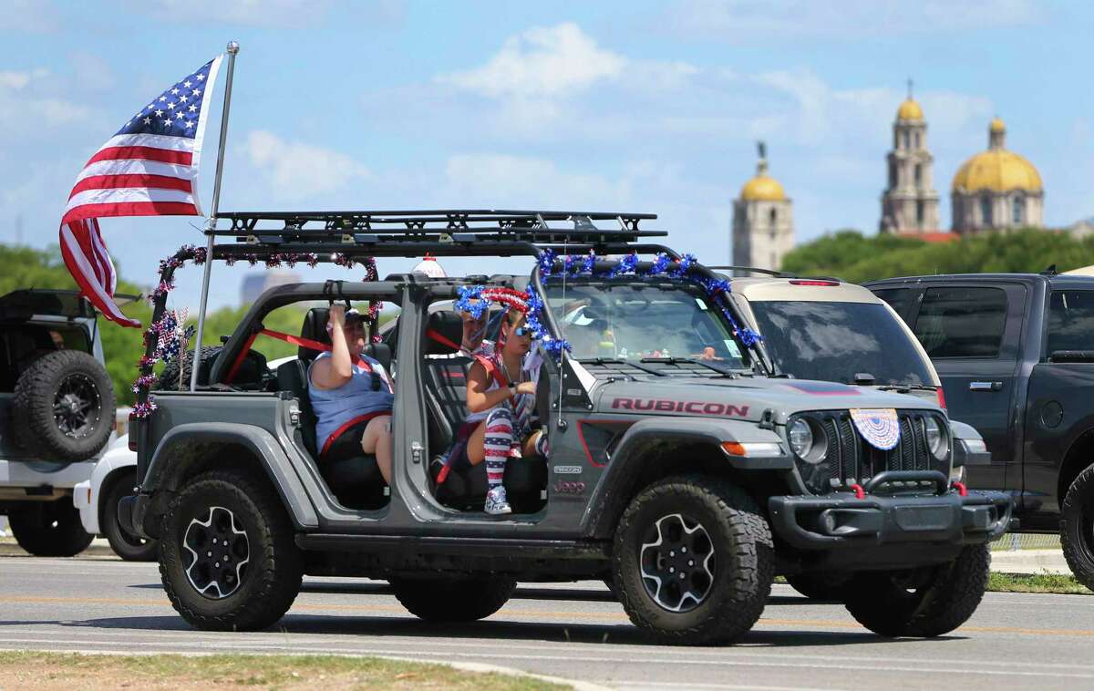 A patriotically decorated Jeep cruises near Woodlawn Lake as people gather to celebrate Independence Day with family and friends on Monday. The hot summer temperature did not deter San Antonians as they claimed their favorite spots to grill hamburgers and await the evening fireworks show.