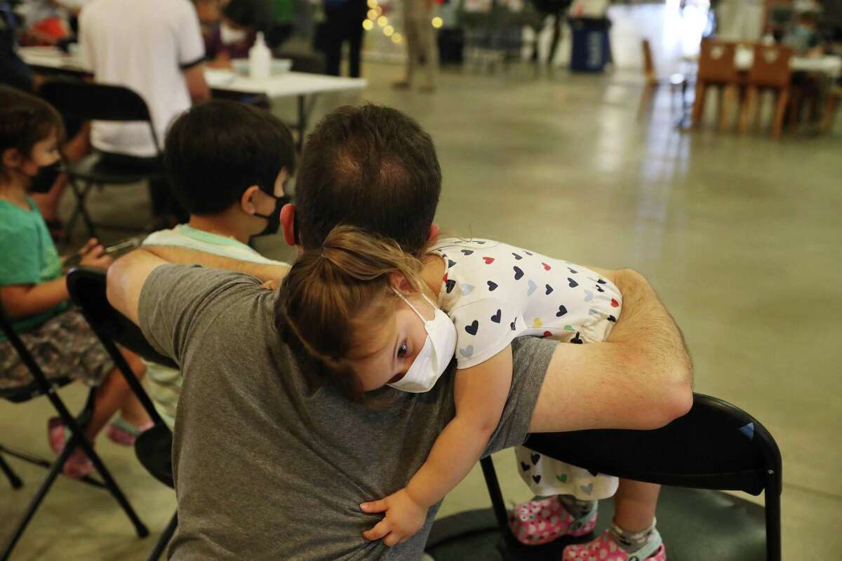 Dora Vicondoa (right) 2, stands on a chair to hug her father John Vicondoa (second from right), of San Jose, after she received her COVID-19 vaccine at a vaccine clinic at the Santa Clara County Fairgrounds on Tuesday, June 21, 2022 in San Jose, Calif.