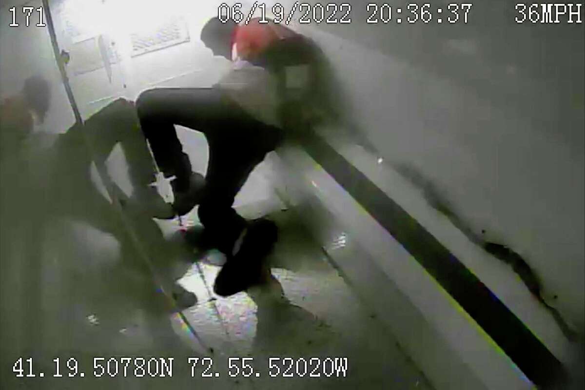 In this photo taken from surveillance video, Richard Cox slides down the back of a police van while being transported after being detained by New Haven Police, June 19, 2022, in New Haven, Conn. Officials in Connecticut said, Wednesday, June 22, 2022, that two New Haven officers have been placed on paid leave and three others were reassigned after Cox was seriously injured in the back of a police van.