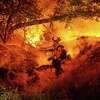 A firefighter douses flames from the Electra Fire in Mokelumne Hill, in Calaveras County, Calif., on Monday, July 4 2022.