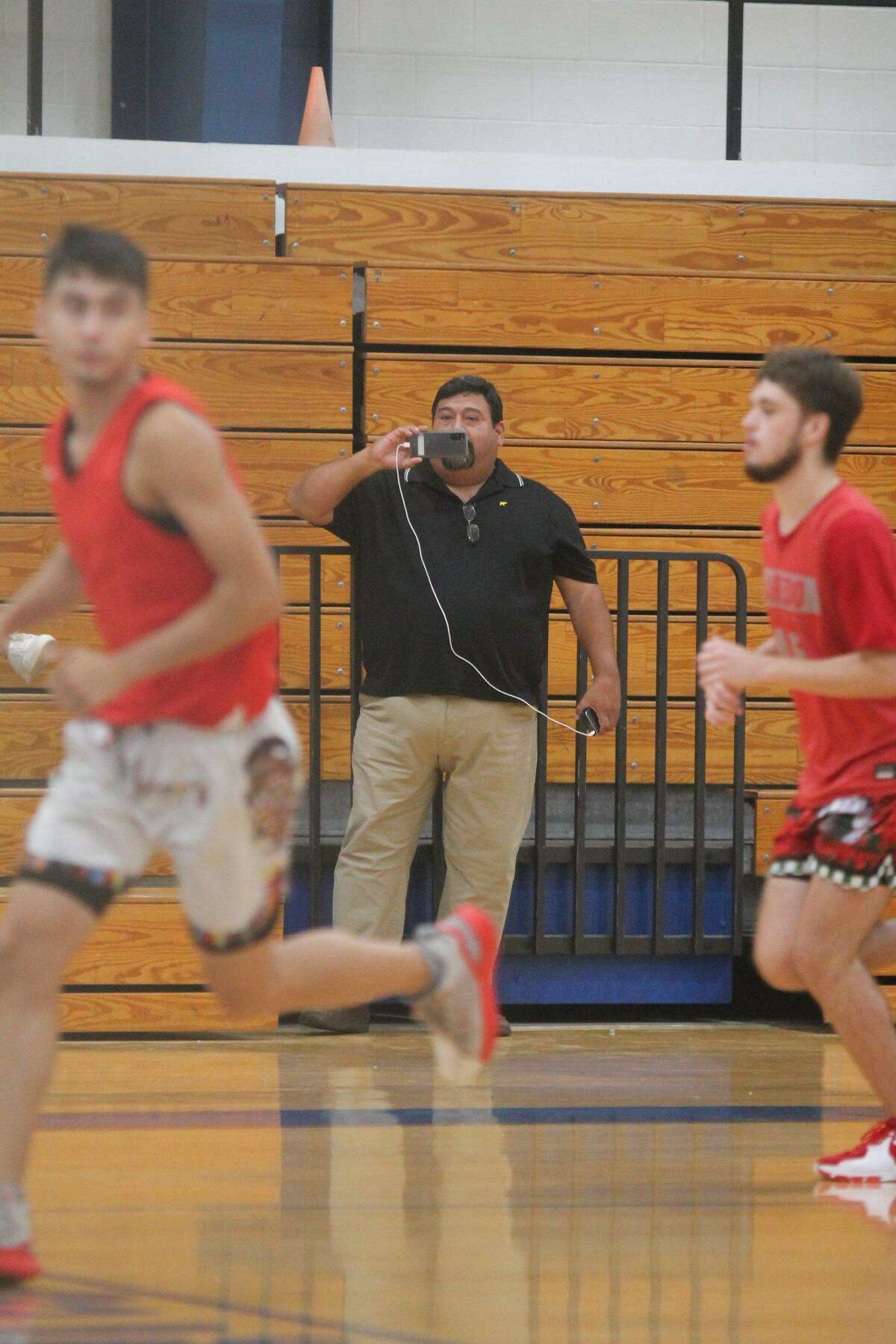 Rafael Emilio Garcia streams St. Augustine boys’ basketball games on his phone.
