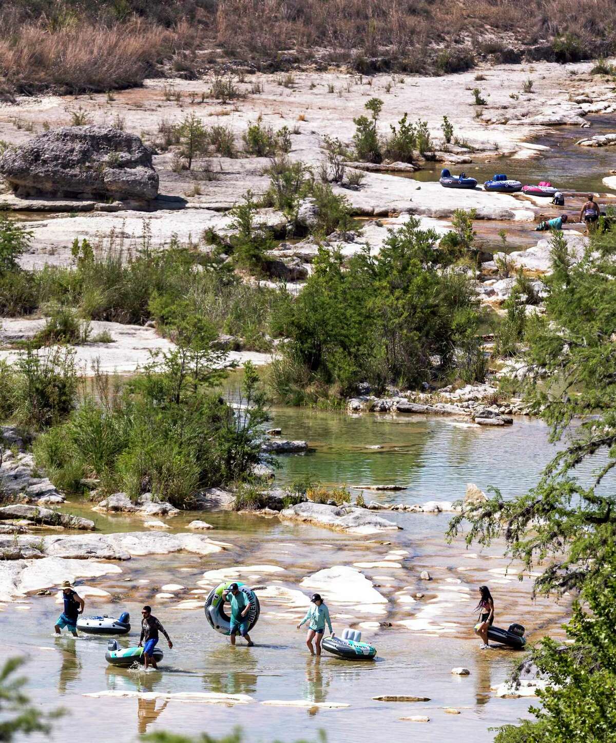 People carry inner tubes on June 23 along a nearly dry Frio River in Garner State Park. The U.S. Geological Survey river gauge downstream from the park in Concan measured zero flow in the river that day, according to the USGS’s water data website.