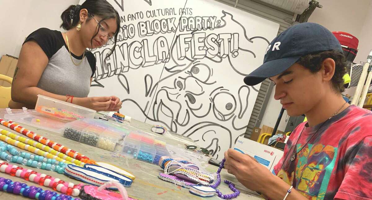 San Anto Cultural Arts intern Tiffany Navarro, left, and Abraham Aguillon-Orsagh, a journalist with El Placazo, the center’s community newspaper, make chancla necklaces for Friday’s Chancla Fest.