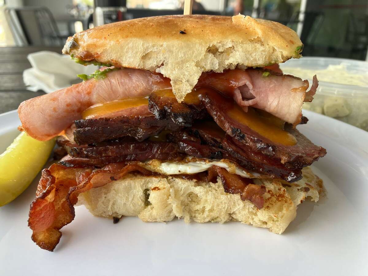 The Rooster with brisket, ham, bacon, cheddar, jalapeno, fried egg, avocado, BBQ sauce on a grilled jalapeno cheddar roll.