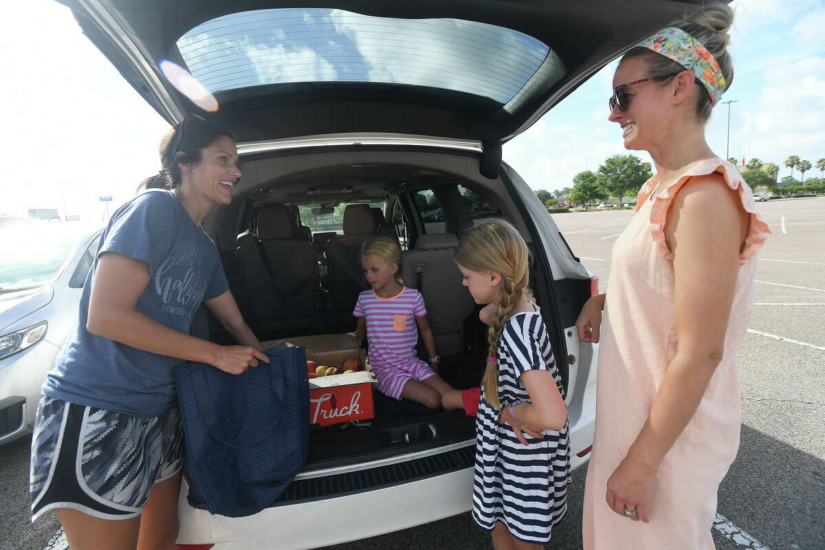 Erin Watts talks with friend Hope Reichenau, with whom she was splitting her order of peaches, at The Peach Truck's summer stop in Beaumont Tuesday morning. Photo made Tuesday, July 5, 2022. Kim Brent/The Enterprise
