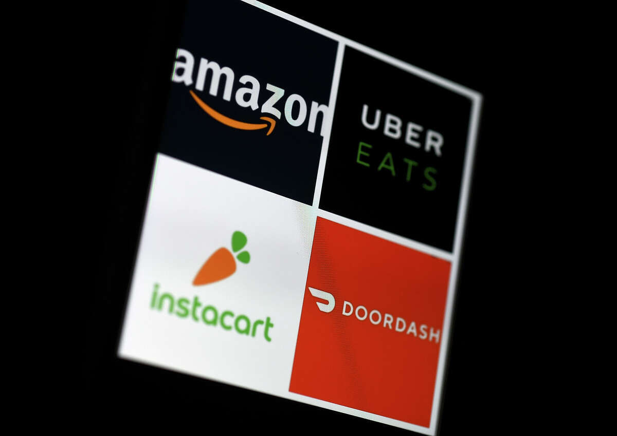 This illustration picture shows delivery applications logos from Amazon, Uber Eats, Instacart and Doordash displayed on a smartphone in 2020.
