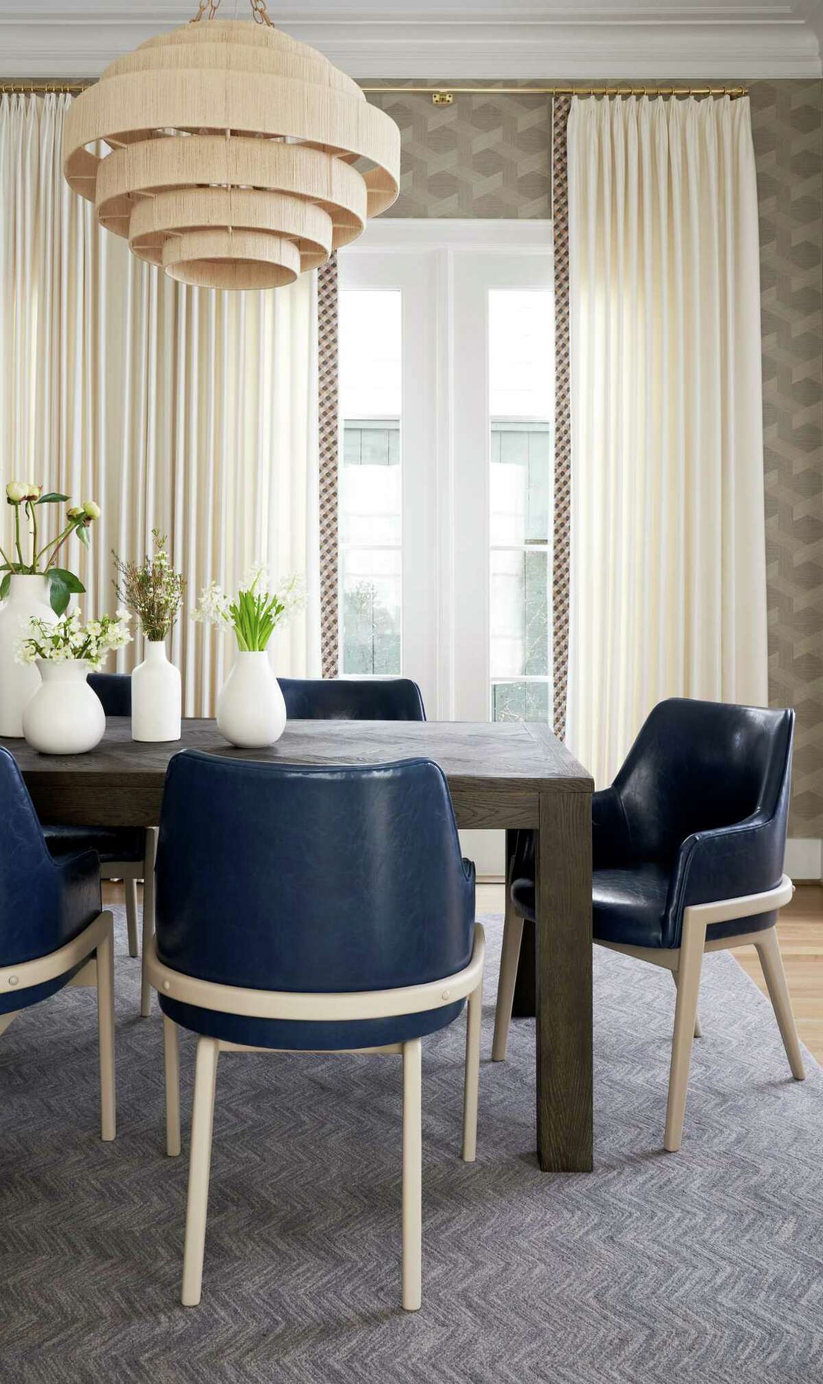 Beautiful Phillip Jeffries vinyl woven sisal wallpaper and chandeliers covered in natural fiber add texture in the dining room.