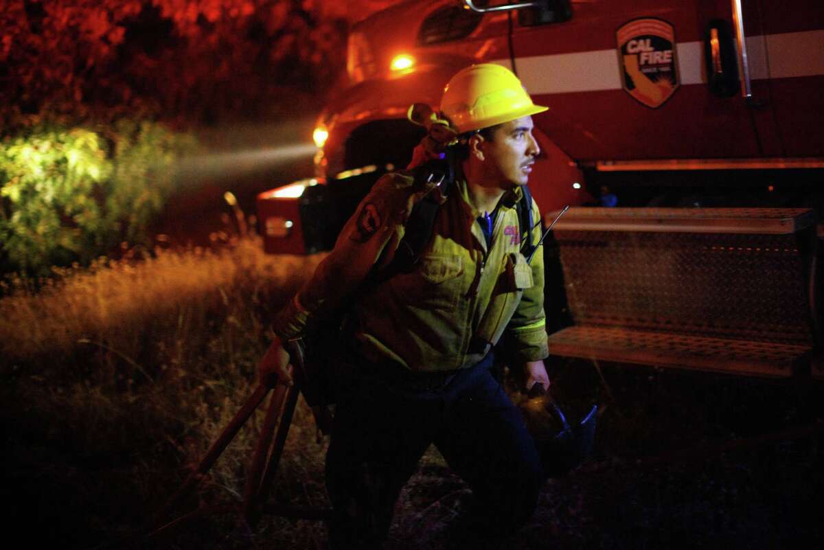 A firefighter pulls a hose line Monday while fighting the Electra Fire on Mokelumne Hill in Calaveras County.
