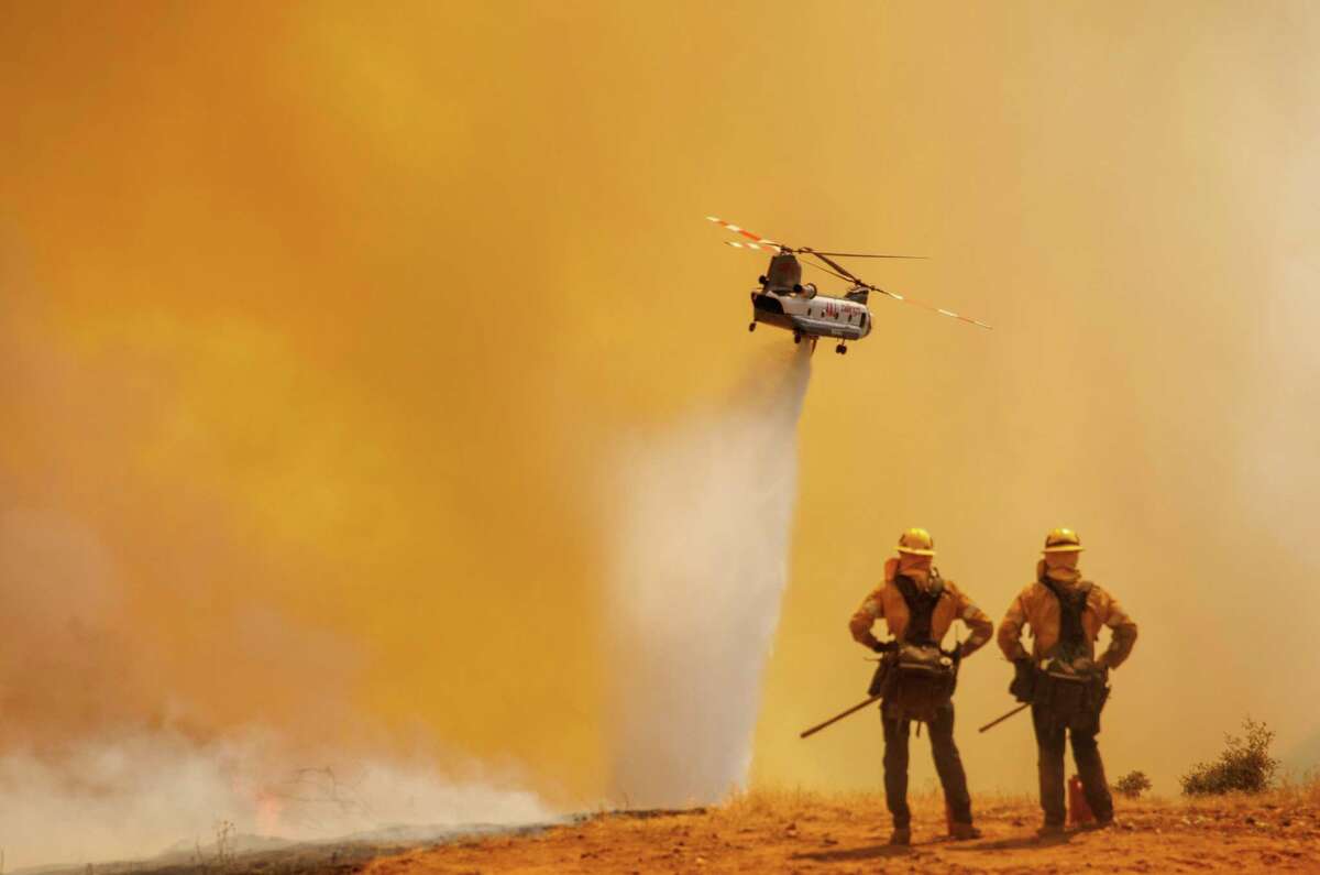 A chinook helicopter drops water on the Electra Fire as firefighters look on off of Quail Drive in Pine Acres Calif., on Tuesday, Jul. 05, 2022.