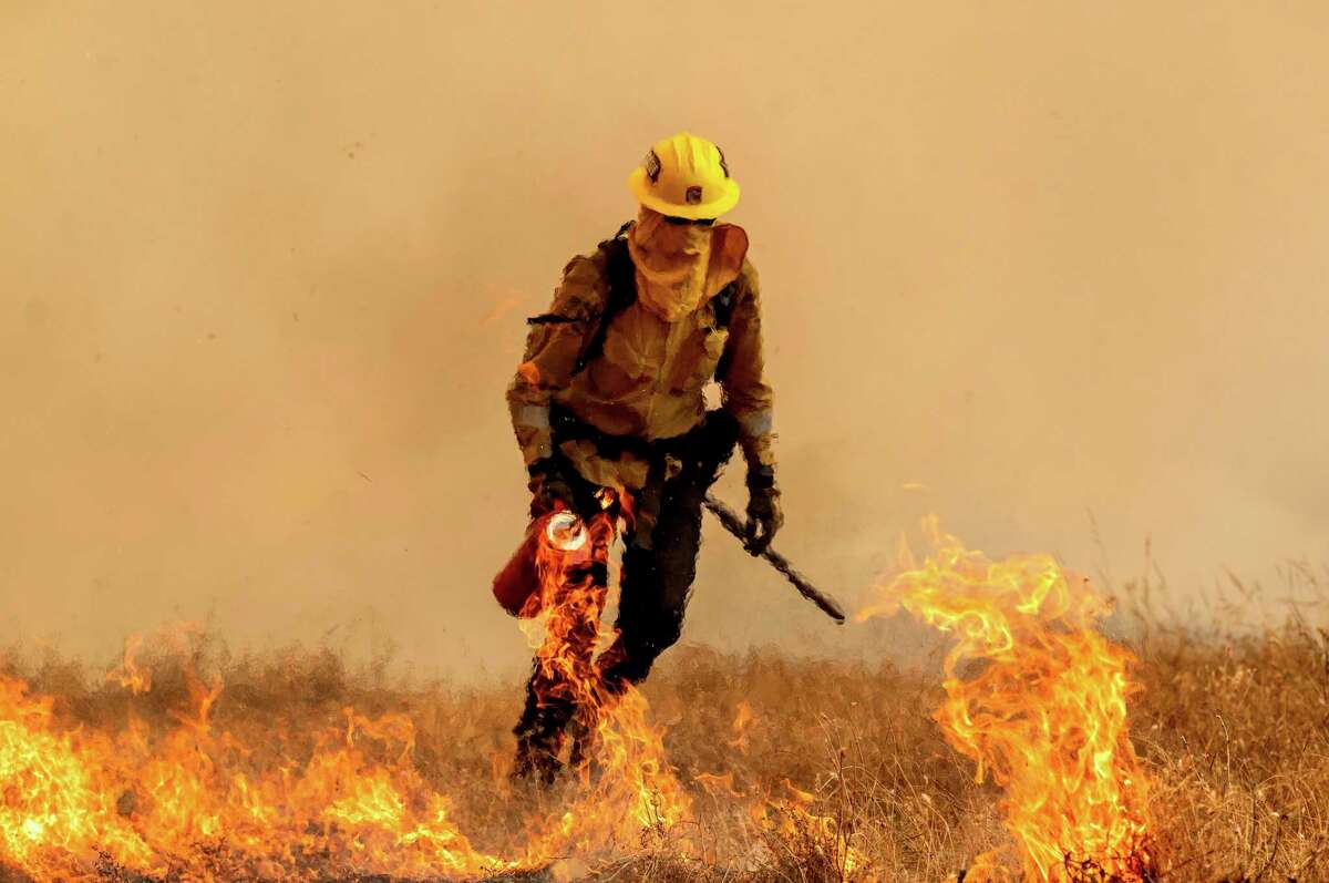 A firefighter burns vegetation while trying to keep the Electra Fire from reaching homes in the Pine Acres community of Amador County, Calif., on Tuesday, July 5, 2022. (AP Photo/Noah Berger)