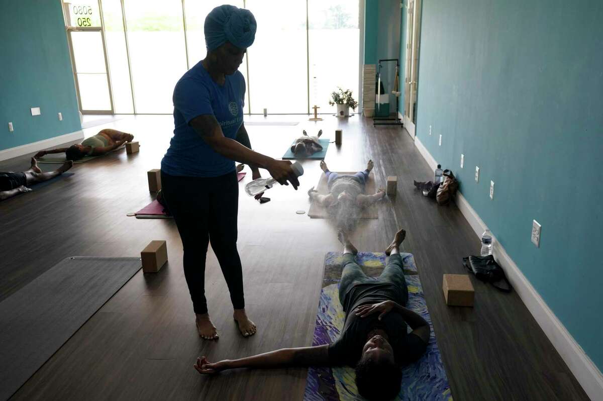 Owner Dana Smith spritzes Alexis Braswell with a calming essential oil at the end of a class at Spiritual Essence Yoga Studio on June 29 in Upper Marlboro, Maryland.