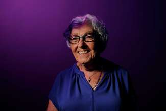 Portrait of Linda Tiefenthal smiling with her purple hair
