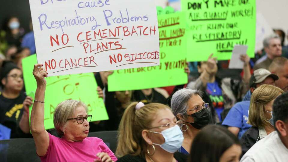 Aldine residents hold up signs in opposition to a proposed concrete batch plant during a public meeting by TCEQ at the East Aldine Management District building on Thursday, April 7, 2022, in Houston.