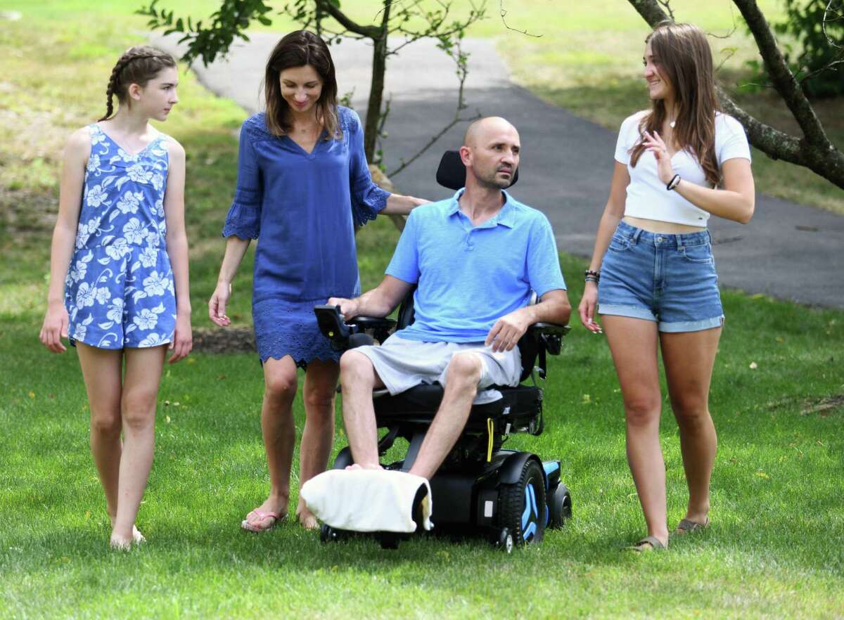 Martin Gibek chats with his wife, Monika Gibek, and daughters, Gabby, 16, and Natalia, 13, outside his home in Stamford, Conn. Wednesday, July 6, 2022. Martin Gibek's pelvis was fractured when he was run over by an excavator at his house on June 10. Friends launched an online fundraiser for Gibek and his family, raising more than $44,000.