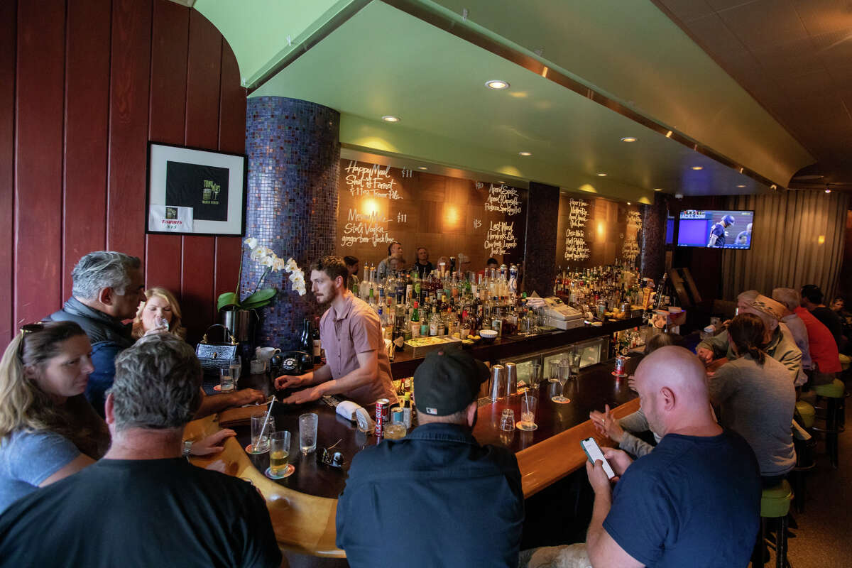 Bartender Ian Whittaker talks to customers at the bar counter at Tony Niks in San Francisco, California July 7, 2022. Scala, a longtime patron and manager, is the new owner of Tony Niks, a former bar in heart of North Beach. He is committed to preserving his legacy.