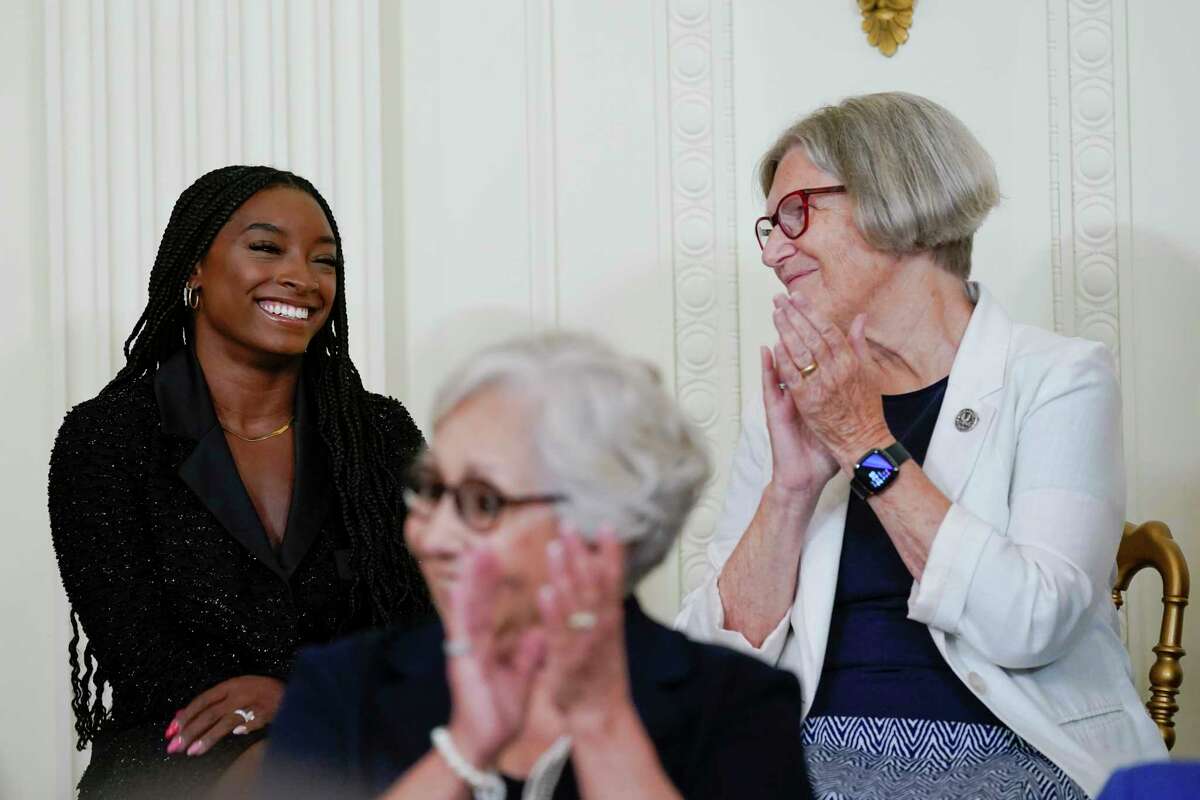 Gymnast and Olympic gold medalist Simone Biles, left, is recognized by President Joe Biden during a ceremony to award the nation's highest civilian honor, the Presidential Medal of Freedom, in the East Room of the White House in Washington, Thursday, July 7, 2022. Biles is the most decorated U.S. gymnast in history, winning 32 Olympic and World Championship medals. Sister Simone Campbell applauds at right. (AP Photo/Susan Walsh)