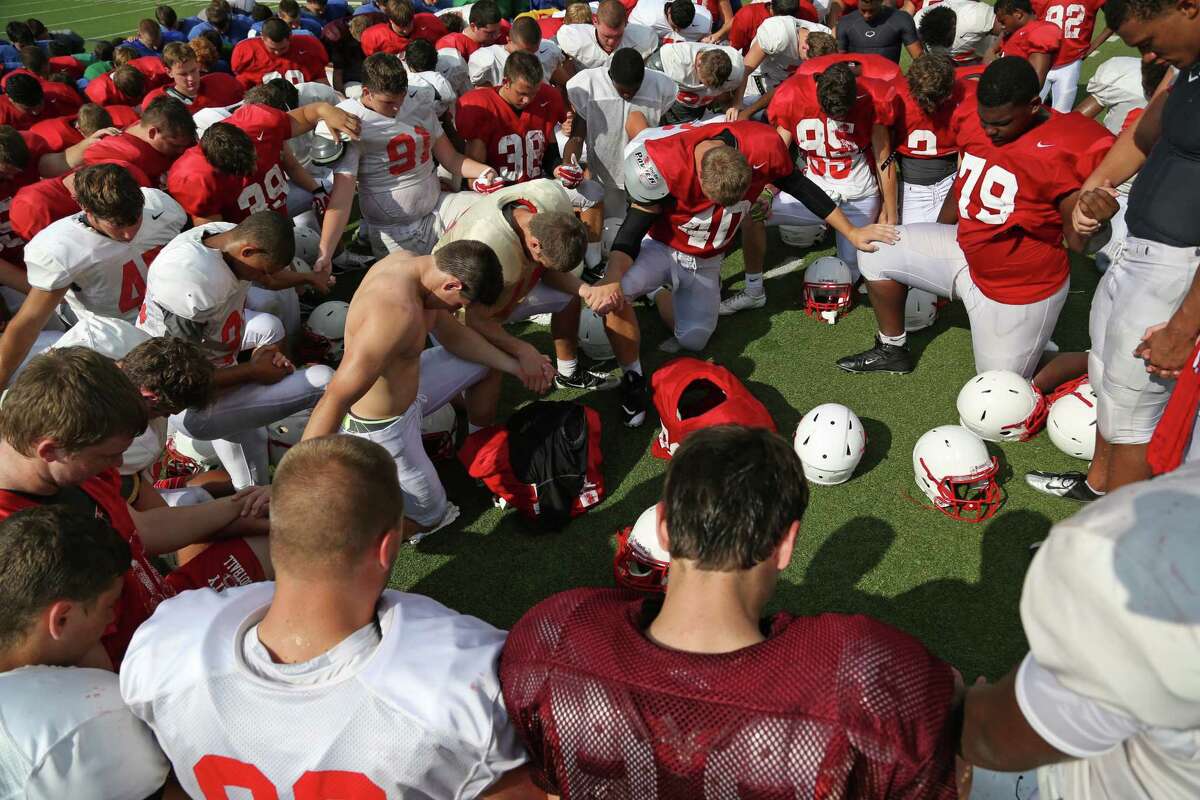 The players participate in a team prayer at the end of Katy High School's fall football practice first day of full pads Friday, Aug. 15, 2014, in Katy, Texas.