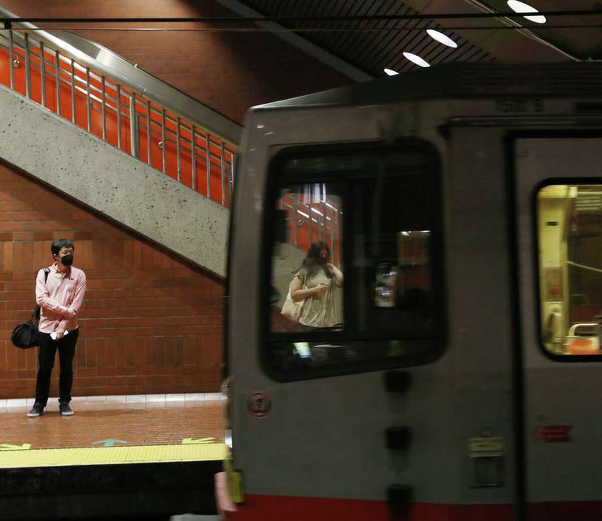 People wait on the platform as a MUNI train arrives at Castro Street Station in San Francisco.