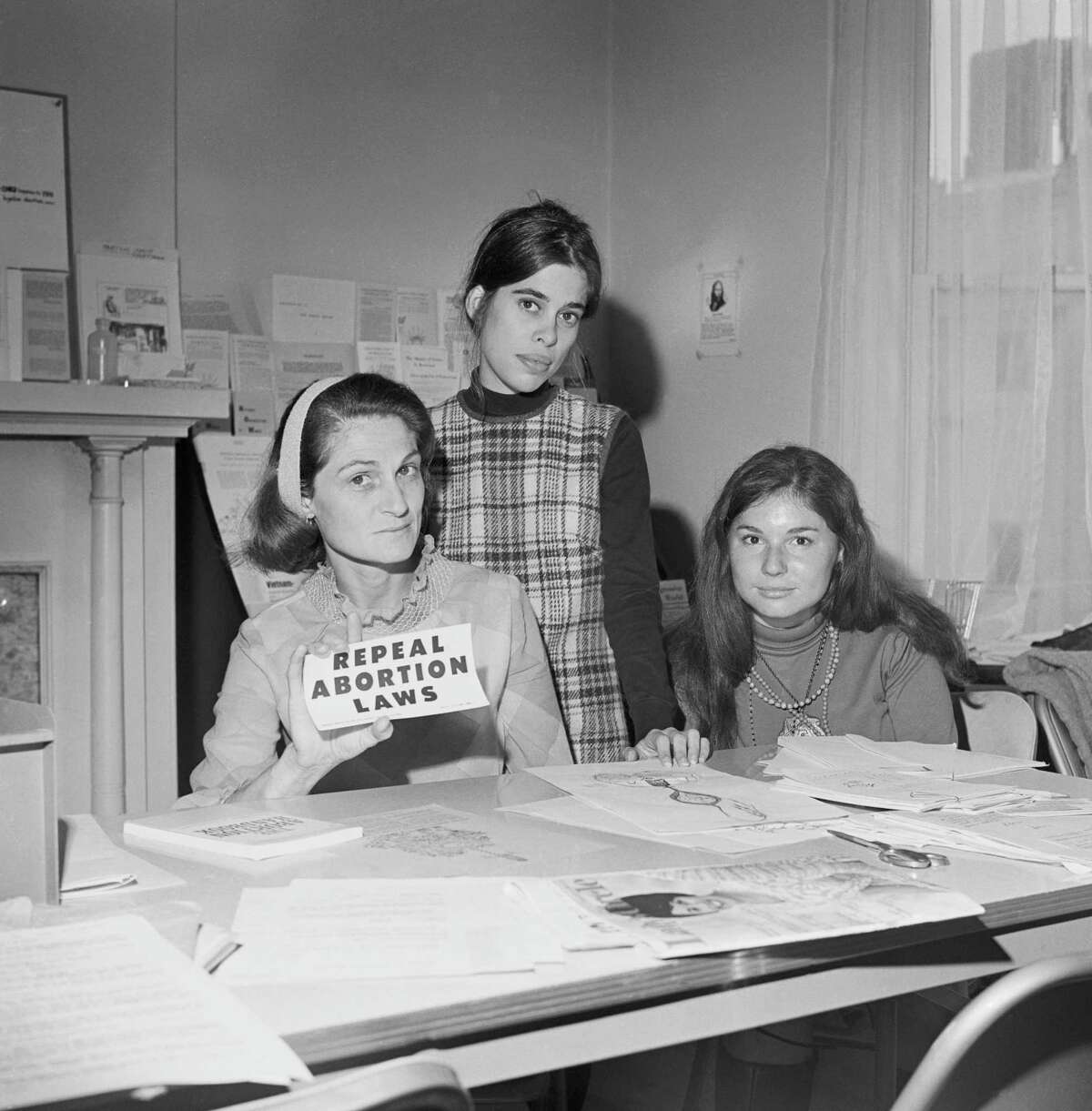 A leader in the movement for unrestricted abortion, Patricia Maginnis stands next to a bulletin board full of abortion information in Sausalito, Calif. in the 1960s.