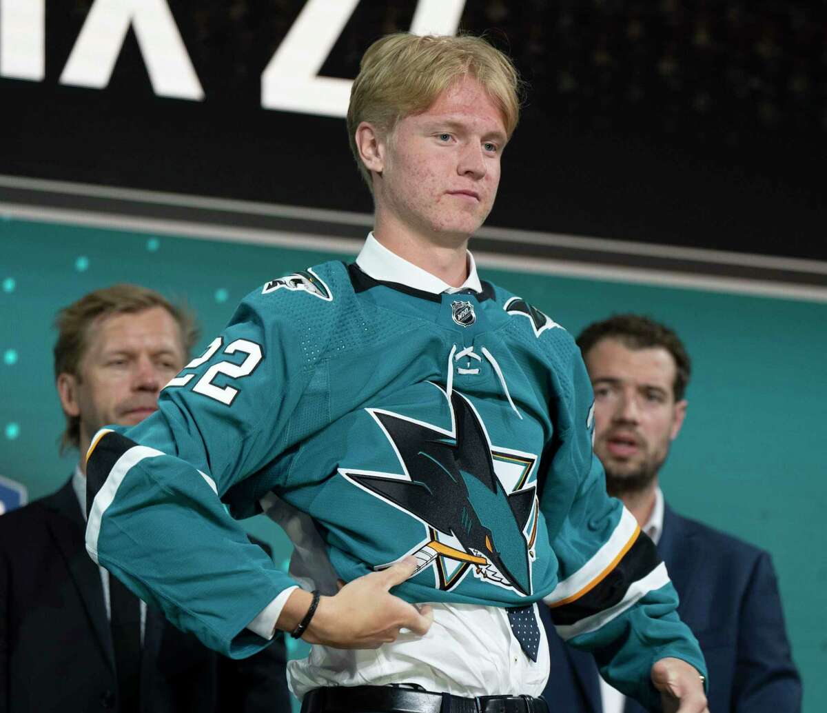 Filip Bystedt puts on a San Jose Sharks jersey after being chosen during the first round of the NHL hockey draft in Montreal on Thursday, July 7, 2022. (Ryan Remiorz/The Canadian Press via AP)