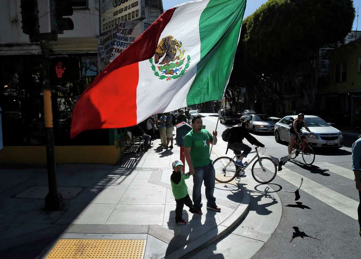 A man carries a large Mexican flag through San Francisco’s Mission District in 2014 after Mexico defeated Croatia in a World Cup soccer game.