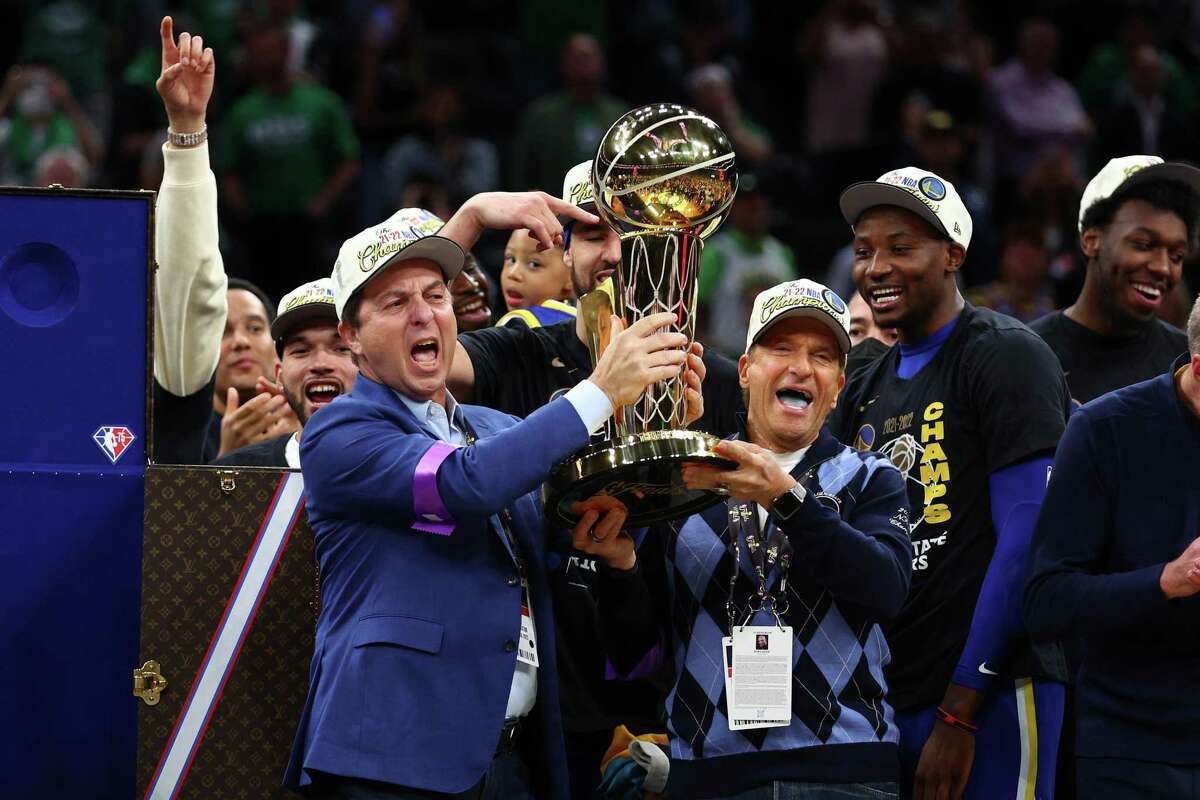 BOSTON, MASSACHUSETTS - JUNE 16: Owners Joe Lacob and Peter Guber of the Golden State Warriors raise the Larry O'Brien Championship Trophy after defeating the Boston Celtics 103-90 in Game Six of the 2022 NBA Finals at TD Garden on June 16, 2022 in Boston, Massachusetts. NOTE TO USER: User expressly acknowledges and agrees that, by downloading and/or using this photograph, User is consenting to the terms and conditions of the Getty Images License Agreement. (Photo by Elsa/Getty Images)