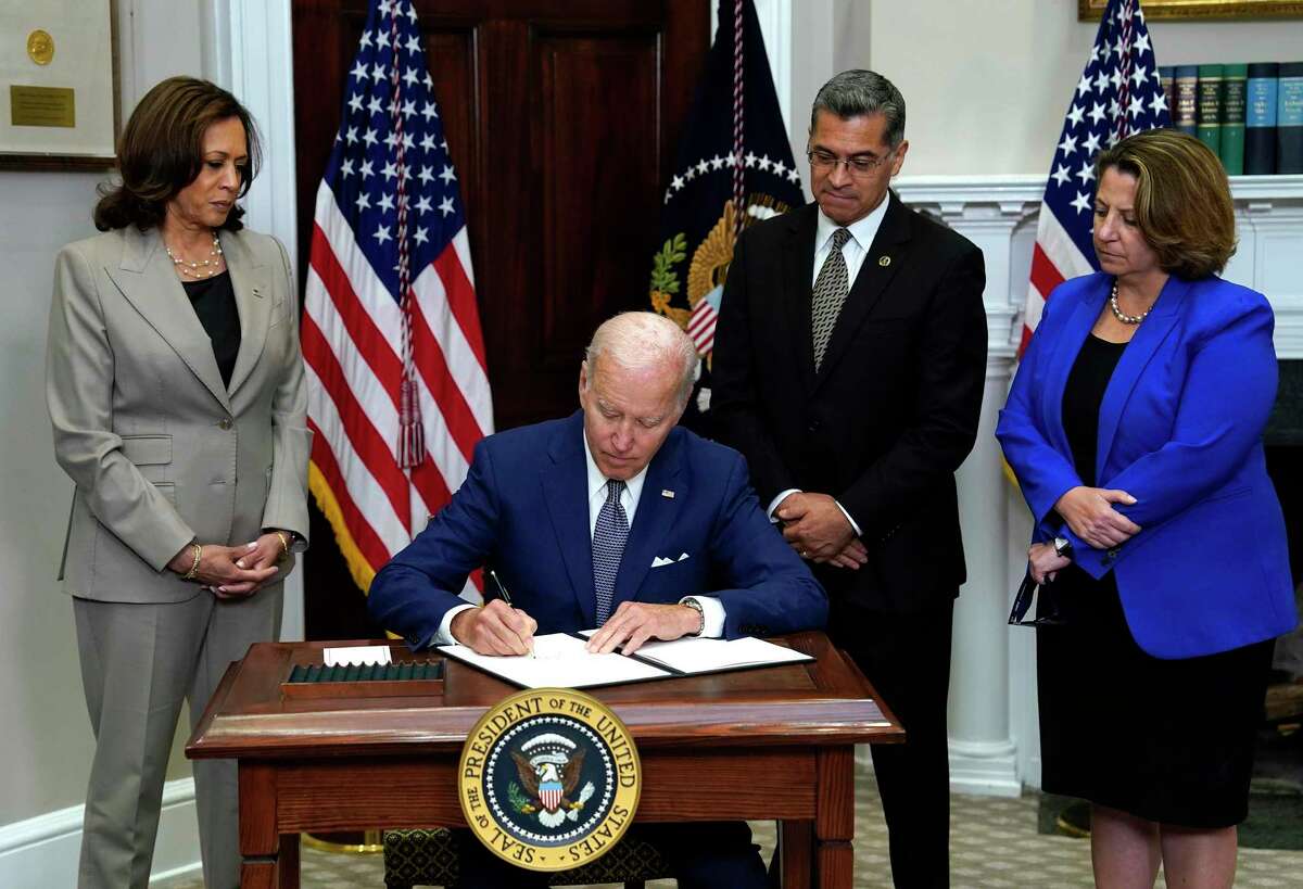 President Joe Biden signs the executive order on access to reproductive health care services in the Roosevelt Room at the White House on Friday, July 8, 2022. Behind Biden are, from left, Vice President Kamala Harris, Health and Human Services Secretary Xavier Becerra and Deputy Attorney General Lisa Monaco.