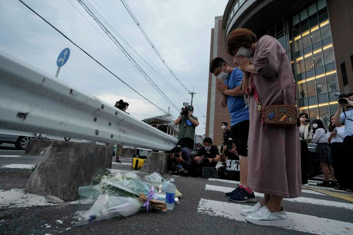 People pray after putting a bouquet of flowers at a makeshift memorial at the scene where the former Prime Minister Shinzo Abe was shot while delivering his speech to support the Liberal Democratic Party's candidate during an election campaign in Nara, Friday, July 8, 2022. Former Japanese Prime Minister Shinzo Abe, a divisive arch-conservative and one of his nation's most powerful and influential figures, has died after being shot during a campaign speech Friday in western Japan, hospital officials said.