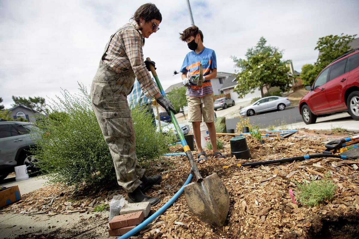 Ana Poe and Levi Edsinger, 9, dig a trench for piping during a greywater installation demonstration at a Vallejo home.