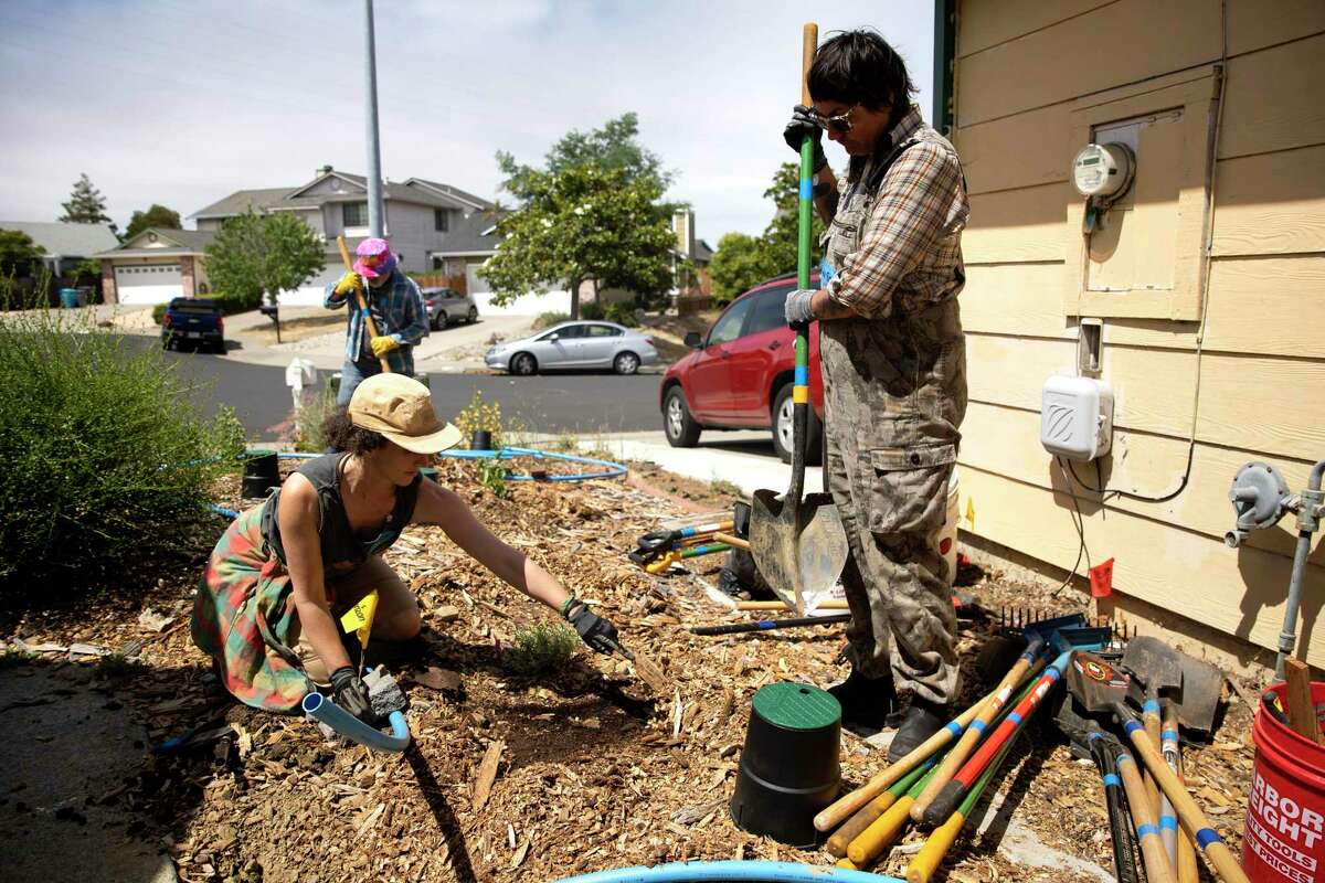 Nina Gordon-Kirsch, with Greywater Action, explains the process for digging mulch basins with volunteer Ana Poe during a greywater installation demonstration at a Vallejo home.