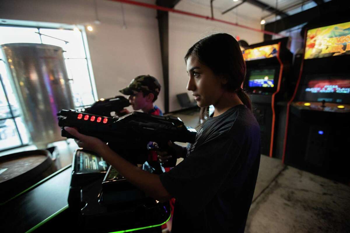 Gunner Skaggs, 11, and Natalia Medrano, 14, play at the arcade Cidercade in EaDo.