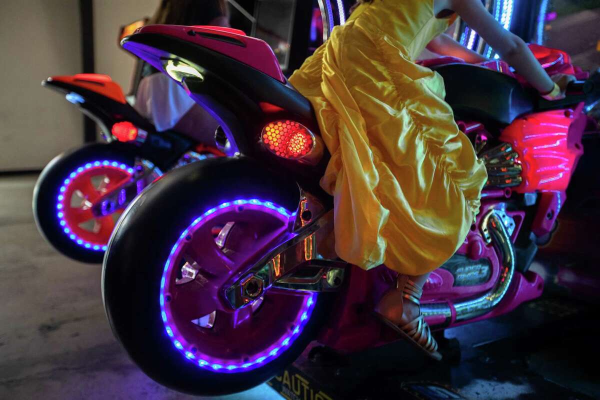 Louise Thompson, 6, wears a princess dress while playing an interactive motorcycling video game at Cidercade in EaDo, Thursday, July 7, 2022, in Houston.