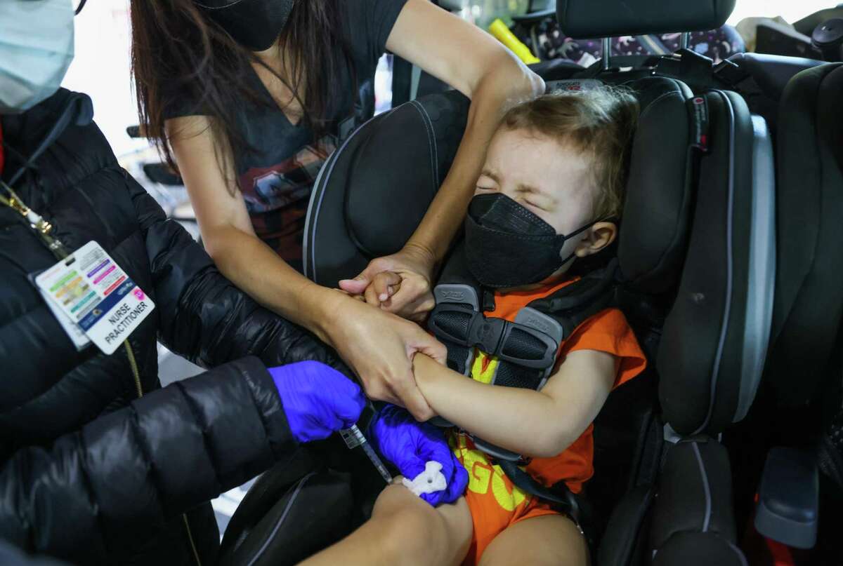 A nurse gives 2-yar-old Zuma Midnight a COVID-19 vaccination as his mother, Gayle Midnight, holds his hands at the UCSF Laurel Heights campus. Some parents are waiting to get their young children vaccinated.