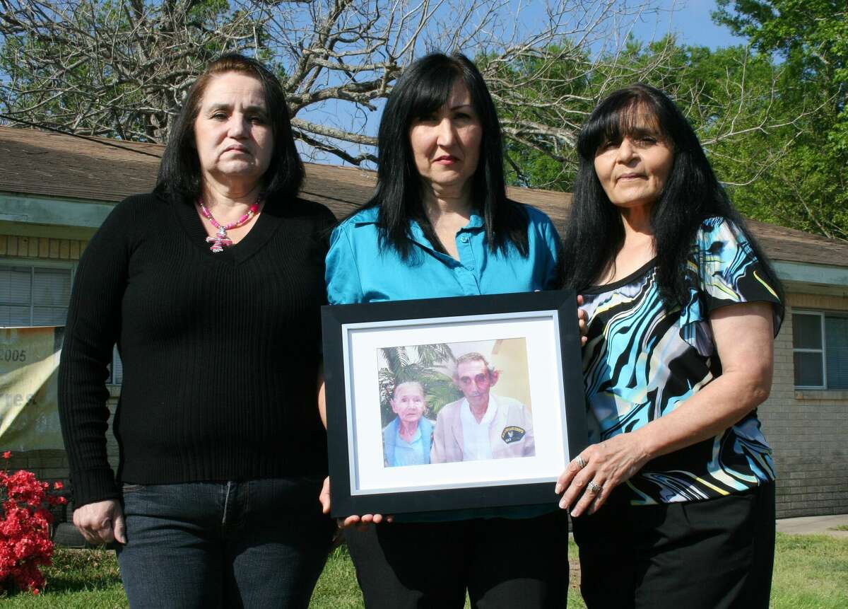 Sisters Janie, Carolina and Norma hold a photo of their parents, Maria De La Luz and Antonio Rodriguez, who were killed in 2005 in the Cleveland home. The passage of time is evident by the tattered and sun-bleached sign that hangs on the home, but the girls and their other siblings are hopeful that one day their parents' murderer will be identified and brought to justice.