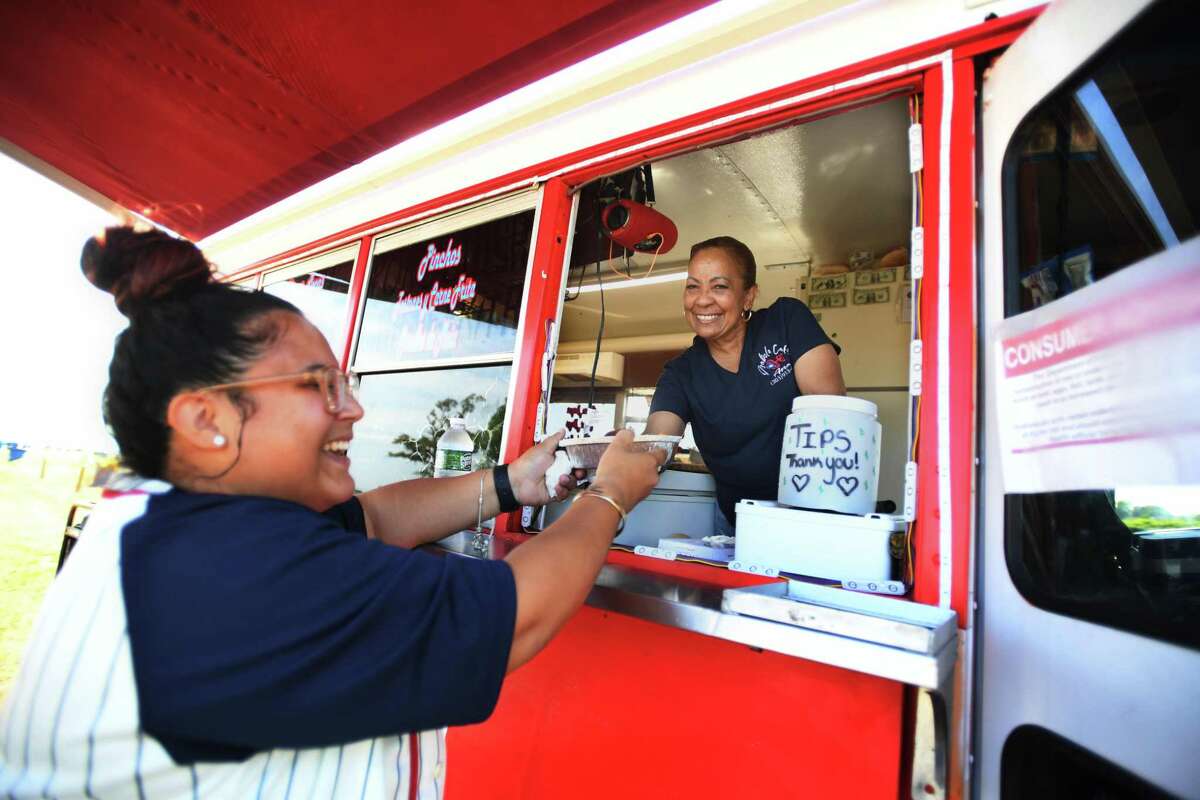 Destiny Rodriguez, left, of Bridgeport, buys lunch from Ana Vargas and her food truck, Isabela Cafe, featuring Puerto Rican specialties, Saturday in the new food truck area at Seaside Park in Bridgeport.