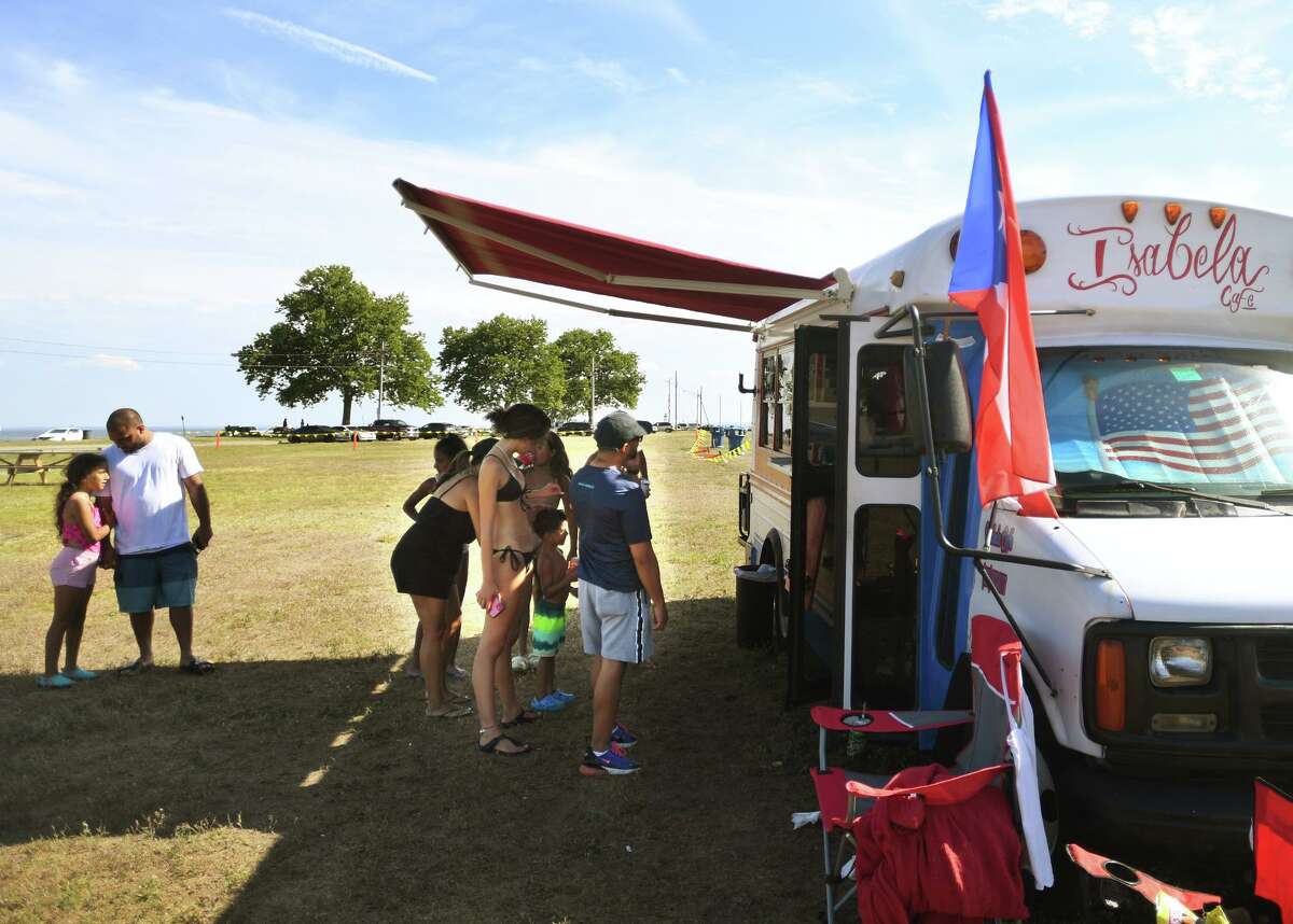 Customers line up outside Ana Vargas' food truck, Isabela Cafe, featuring Puerto Rican specialties, in the new food truck area at Seaside Park in Bridgeport, Conn. on Saturday, July 9, 2022.
